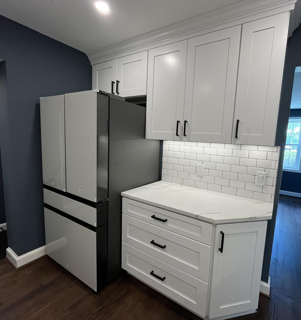 A clean, modern kitchenette with white cabinets and a stone countertop