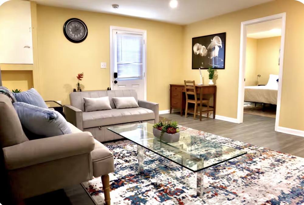 Living room with a sofa, glass coffee table and colorful rug
